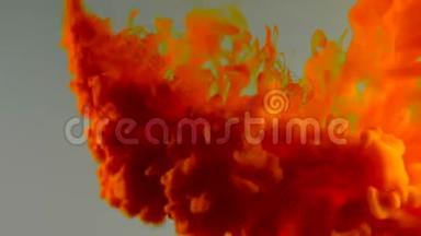 墨水在水里。 橙色的油漆在水中反应，形成抽象的云层。 在灰色上<strong>蜕变</strong>。 艺术背景